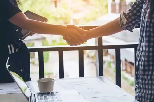 Two people shaking hands over a table